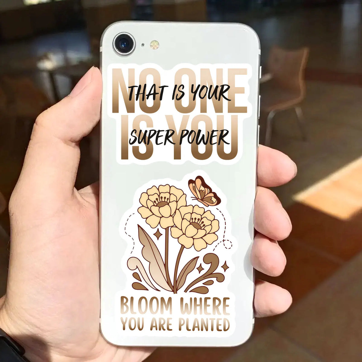 A white phone case features a motivational quote in brown text and a floral design, saying That is your super power Bloom whe