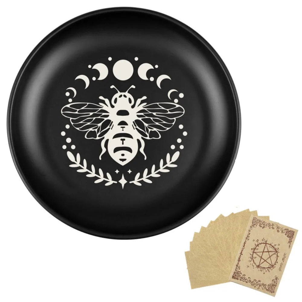 Assiette en céramique noire avec une silhouette d'abeille blanche entourée de lunes et d'une couronne de laurier.