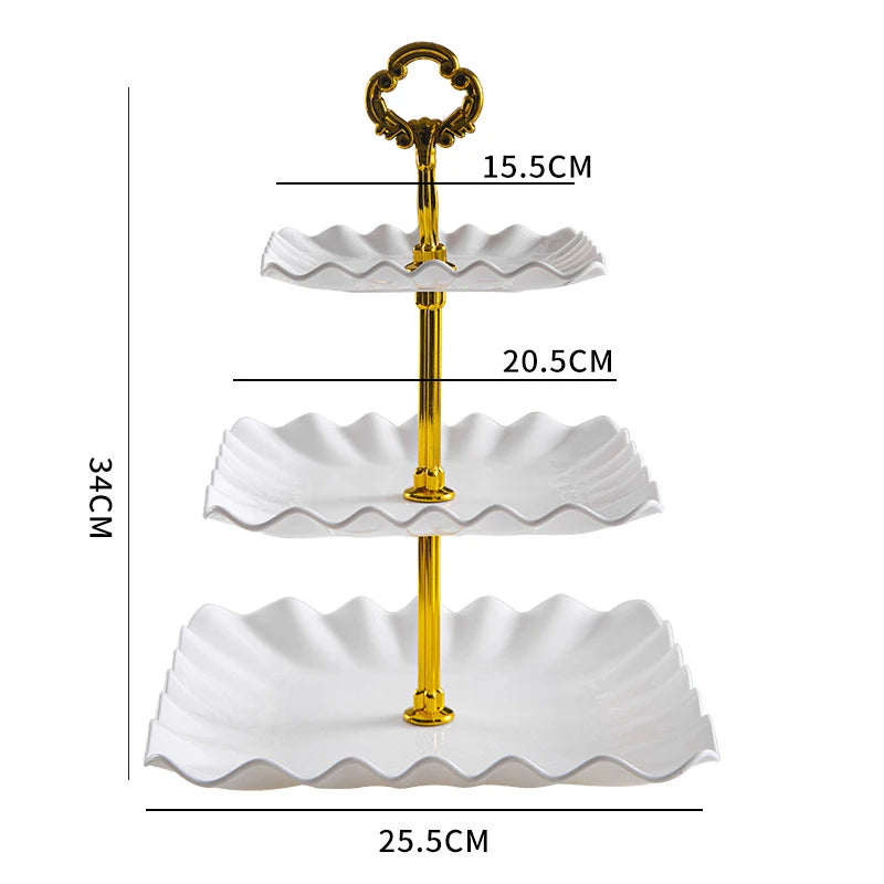 A three-tier gold-colored plastic dessert stand with white scalloped plates.
