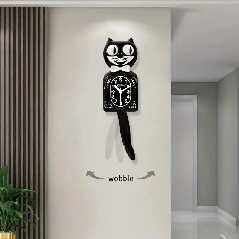 A black cartoon cat wall clock with a white bow and swinging tail mounted on a white wall.