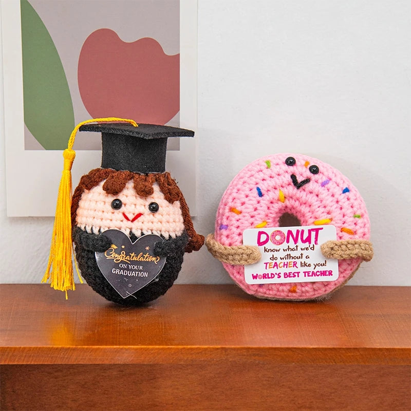 Handmade crochet potato doll with a graduation cap and inspirational tag on a wooden surface.