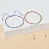 A handmade boho glass bead bracelet with an adjustable cord, featuring blue and red beads.