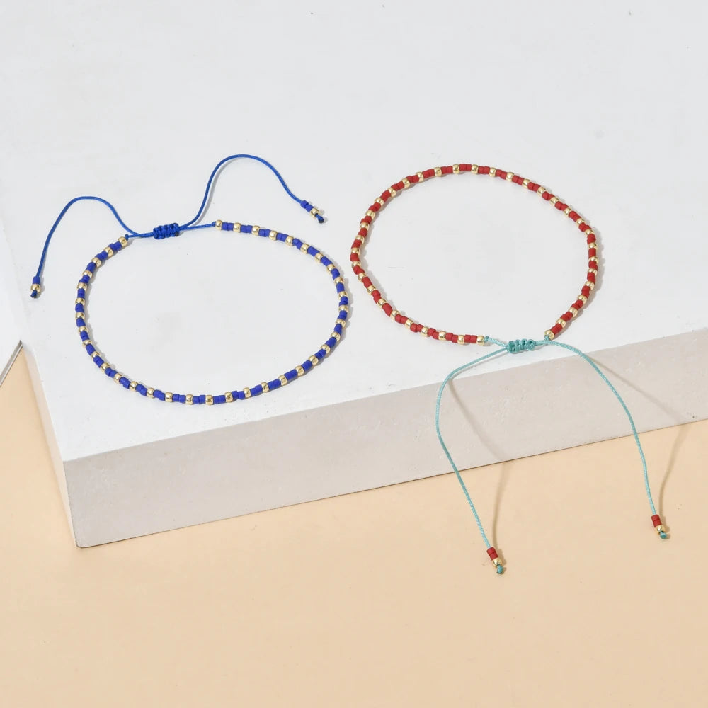 A handmade boho glass bead bracelet with an adjustable cord, featuring blue and red beads.