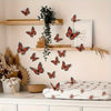 A display of 3D monarch butterfly wall decals on a light-colored wall and wooden shelves.