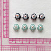 A collection of black and white resin mini penguin figurines arranged on a white background next to a ruler.