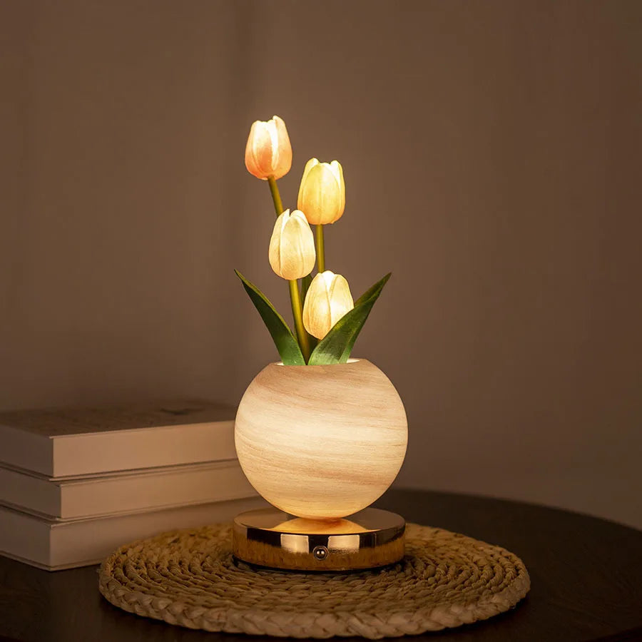 A vase holds three glowing yellow tulips, illuminated by a warm light, resting on a woven mat.