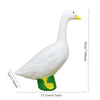 A white goose garden statue with a yellow beak and green base, shown in profile.