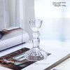 Elegant clear glass pillar candle holder shown on a wooden surface with a measuring scale.