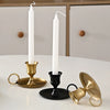 A set of elegant brass and black metal candle holders with handles displayed on a white table.