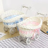 White faux rattan woven storage basket with handles and light blue ribbon accents on a black grid surface.