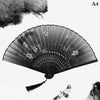 A black and white photograph of a hand carved bamboo folding fan with intricate patterns and a small bird flying below it.