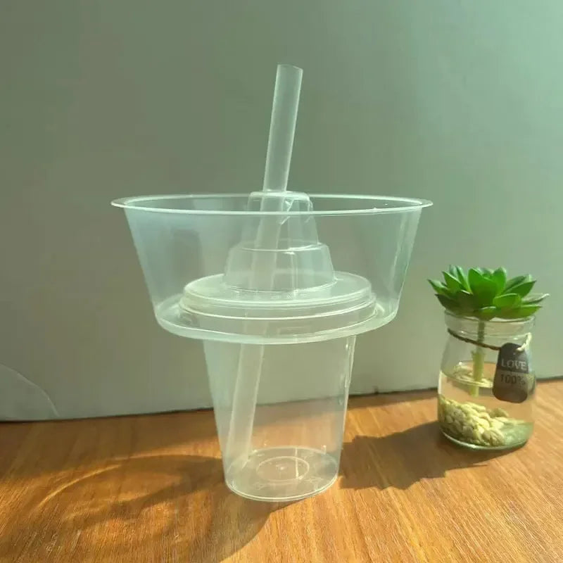 A clear plastic cup with a straw is shown next to a glass jar containing green herbs or fruit pieces.