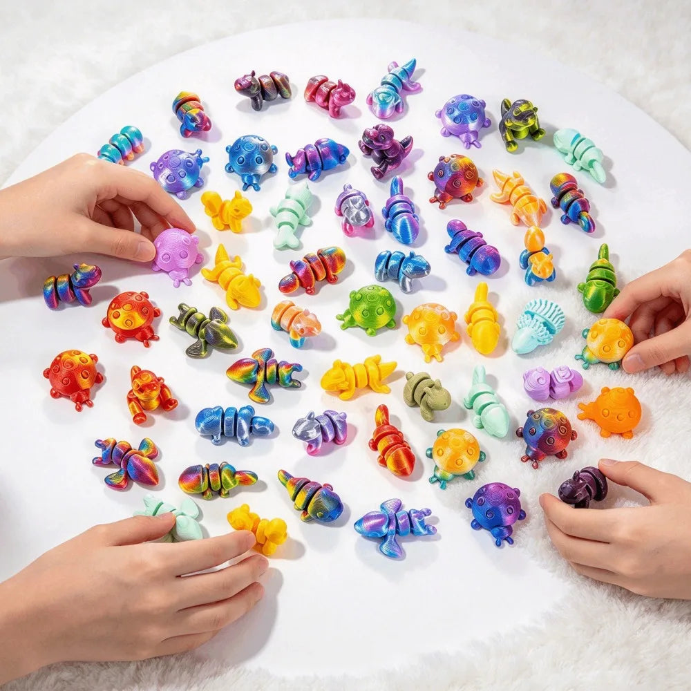 Hands are placing colorful 3D printed articulated animal figurines onto a white surface.