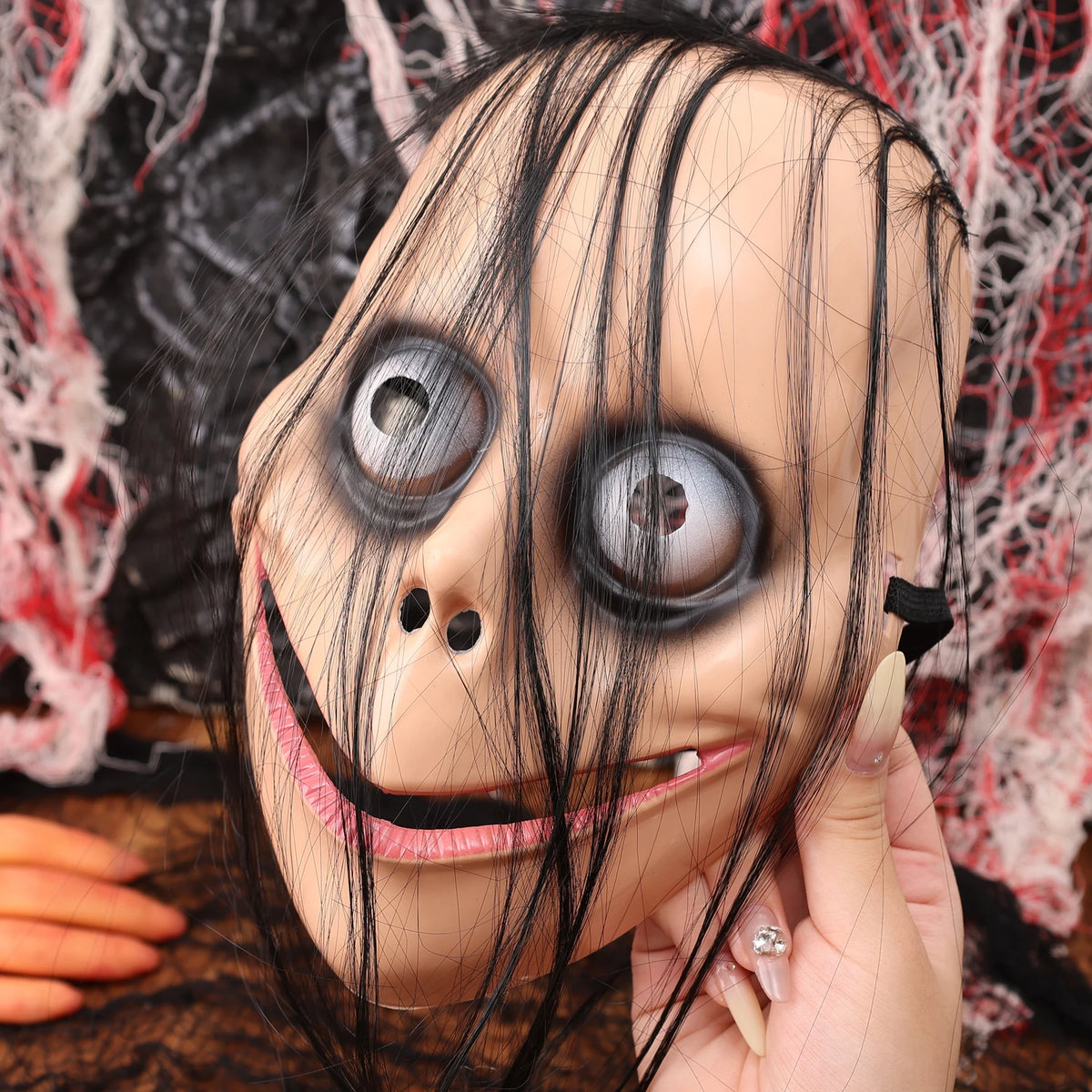 A close-up of a full face horror costume mask resembling a creepy clown with large, glassy eyes and black hair.