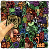 A hand holds a black glow-in-the-dark graffiti design sticker featuring a skull face on a mug.