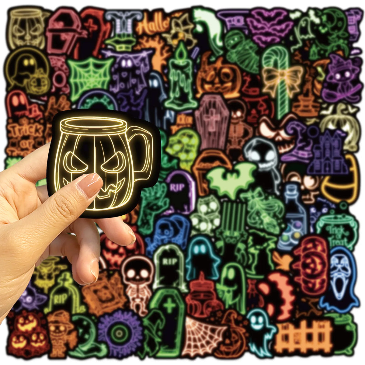 A hand holds a black glow-in-the-dark graffiti design sticker featuring a skull face on a mug.