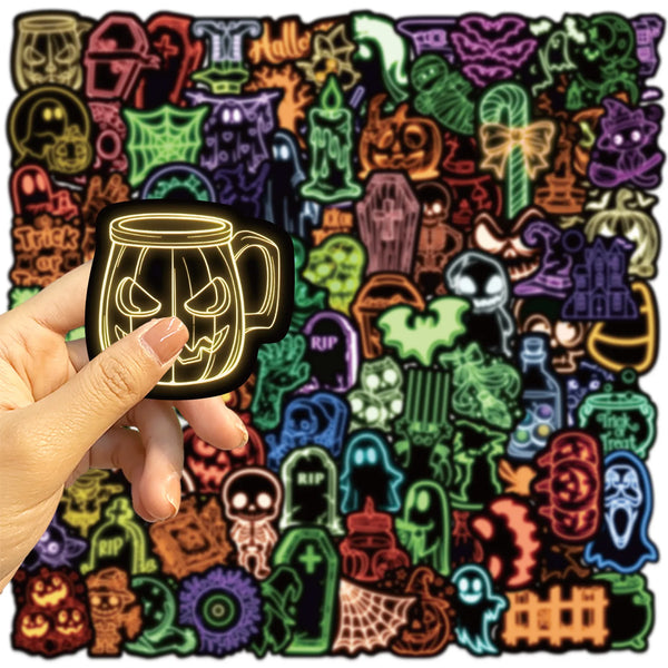 A hand holds a black glow-in-the-dark graffiti design sticker featuring a skull face on a mug.