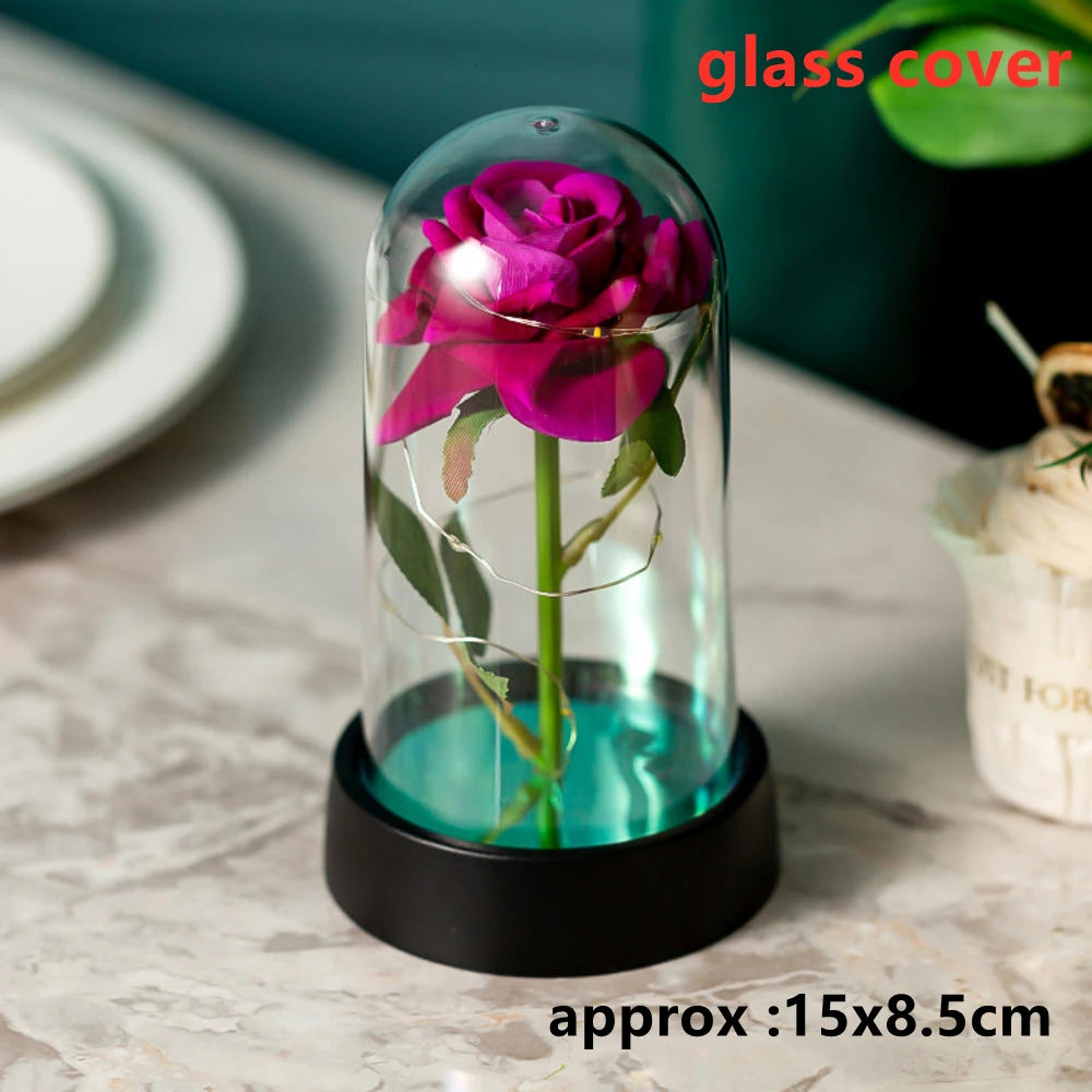 An artificial purple rose flower displayed inside a glass dome on a black base.