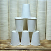 A display of white reusable disposable paper cups arranged in a vertical grid and a row on a wooden surface.