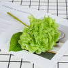 A cluster of bright green artificial hydrangea leaves and stems displayed on a white paper with black grid lines.