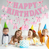 A pink glitter bow birthday banner hangs above a table with children and cupcakes.