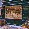 A display of Christmas gingerbread house window stickers and decorations in a storefront window covered with snow.