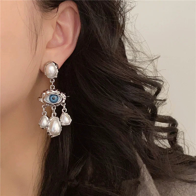 Silver pearl drop earrings featuring a blue eye motif and dangling pearls
