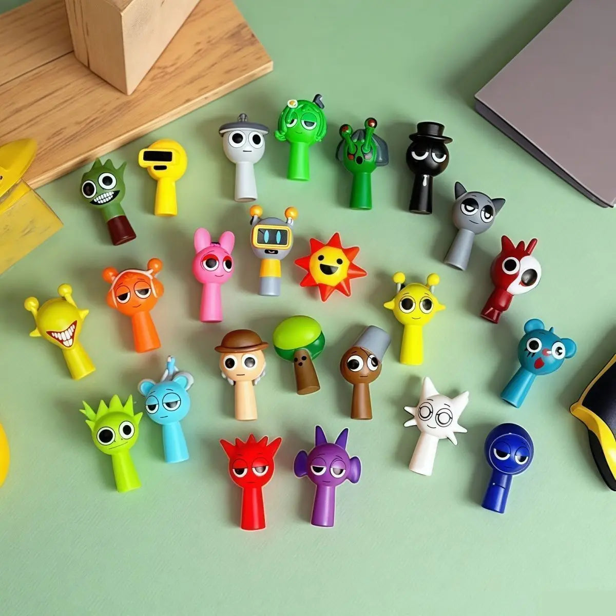 A collection of colorful handcrafted musical figurines in various shapes and colors arranged on a light green surface.