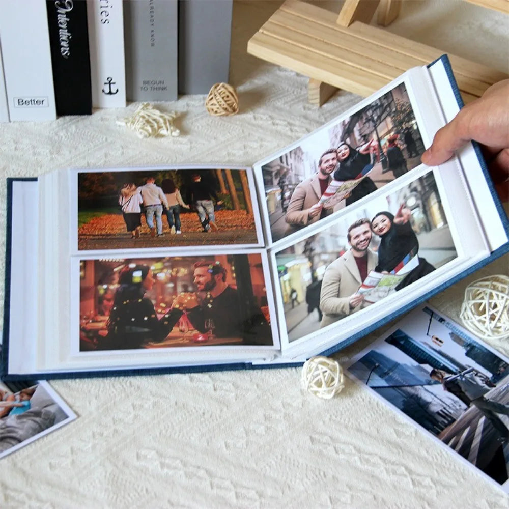 An open linen cover photo album displaying several candid photographs of couples and people.