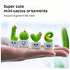 A hand holds four small resin succulent cacti ornaments in various green shades for home decor.