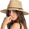 A woman wearing a wide brim straw sun hat while touching her mouth.