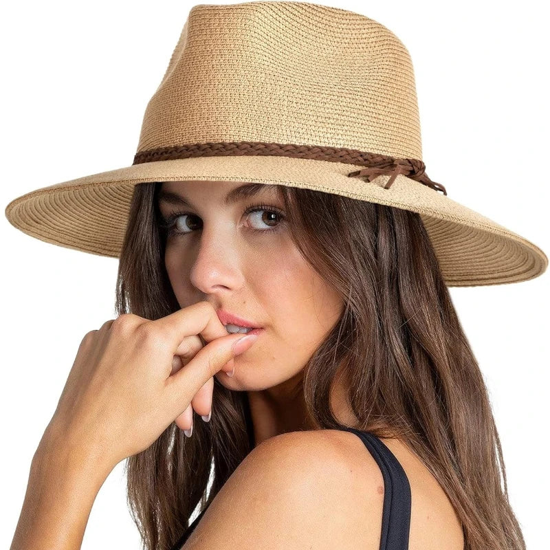 A woman wearing a wide brim straw sun hat while touching her mouth.