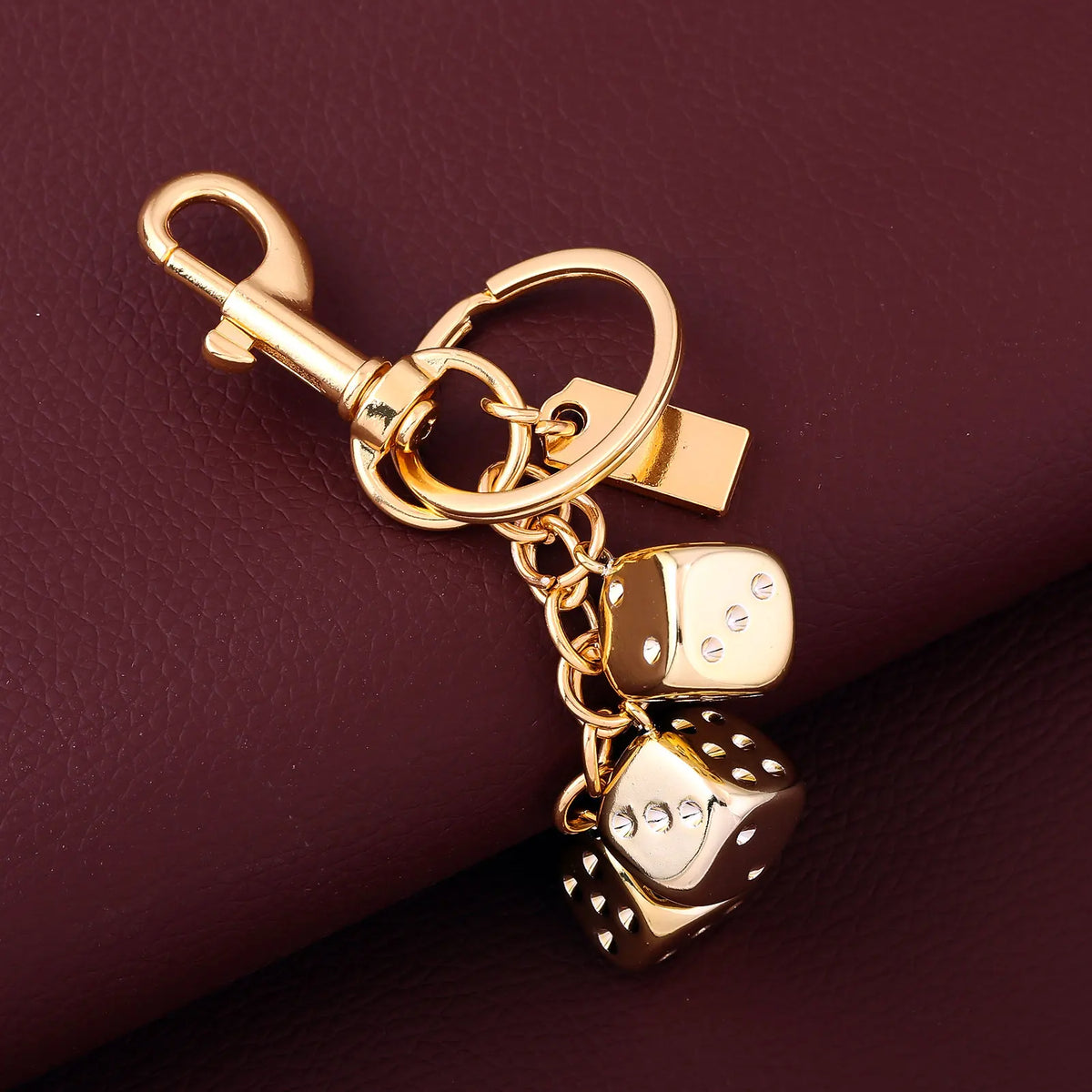 A gold-colored dice keychain with a lucky charm design attached to a split ring.