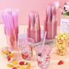 A collection of pink disposable plastic cocktail cups and straws are displayed on a light surface.