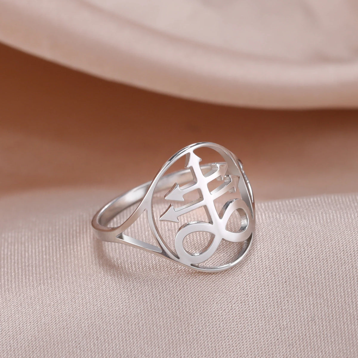Silver signet ring featuring a Leviathan cross symbol on a light pink fabric background.