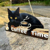A black cat illustration with a steaming coffee cup design on a rustic wooden hanging sign.