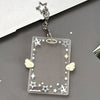 Clear acrylic photocard holder keychain with star and wing designs attached to a silver chain.