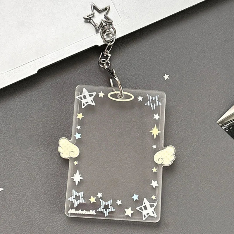 Clear acrylic photocard holder keychain with star and wing designs attached to a silver chain.