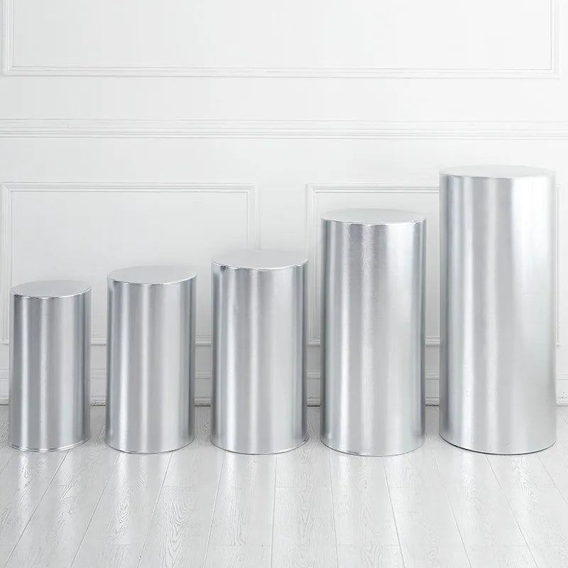 A row of polished silver cylinder stands used as decor for weddings and events.