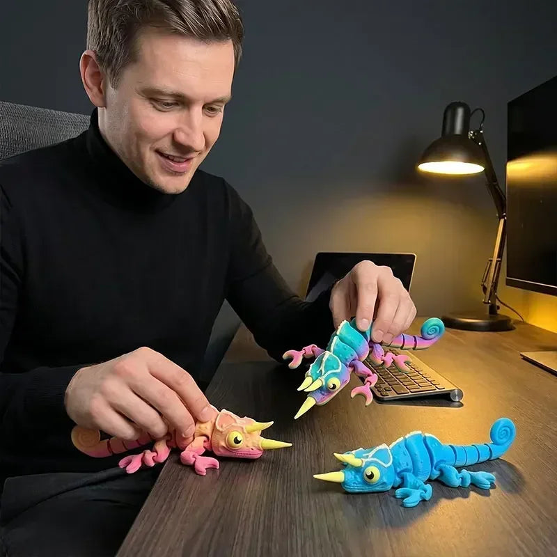 A man is holding and examining glow in the dark 3D printed chameleon fidget toys on a wooden table.