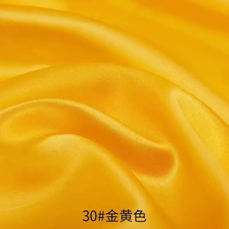 Close-up of flowing golden yellow satin fabric folds.