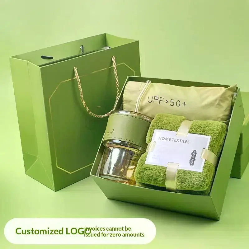 A green gift box contains a tumbler, towel, and UPF sun protection item.