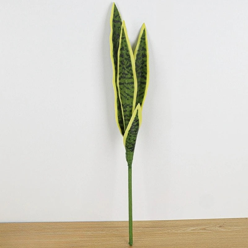 Una planta artificial alta y esbelta con hojas verticales verde amarillento y tallo verde.