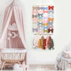Wall-mounted headband holder displaying various pastel colored bows and hair accessories