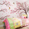 Pink cherry blossom tree wall stickers decorating a bedroom wall with pink and green floral patterns