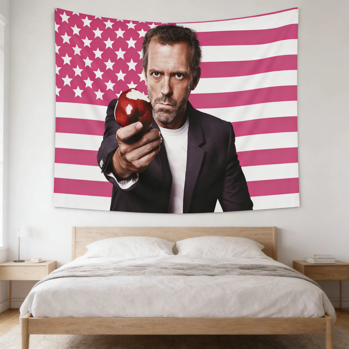 Un hombre sostiene una manzana roja contra un tapiz de decoración con la bandera estadounidense a rayas rosa y blanca.