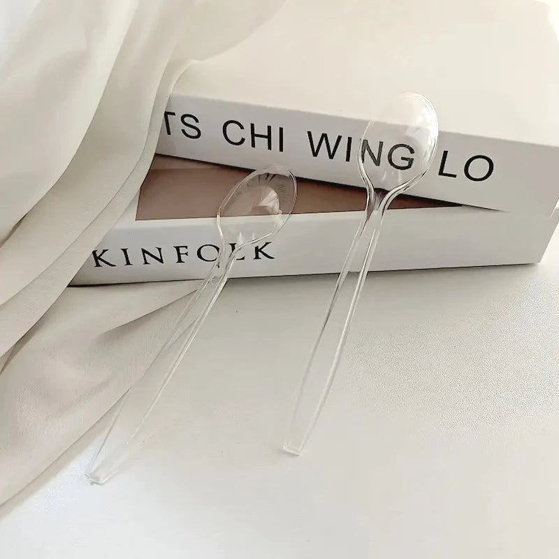 A clear plastic cutlery set is displayed on a white surface next to a book.