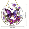 A circular acrylic hummingbird suncatcher featuring purple and yellow flowers and butterflies hanging by a gold string.