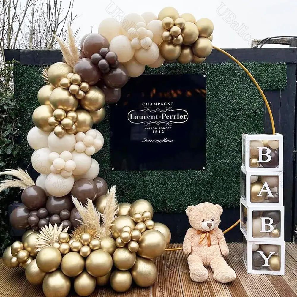A large arrangement of brown and gold latex balloons decorated with dried grasses and leaves for a baby shower or birthday di
