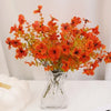 An artificial autumn bouquet featuring vibrant orange silk flowers displayed in a clear glass vase.